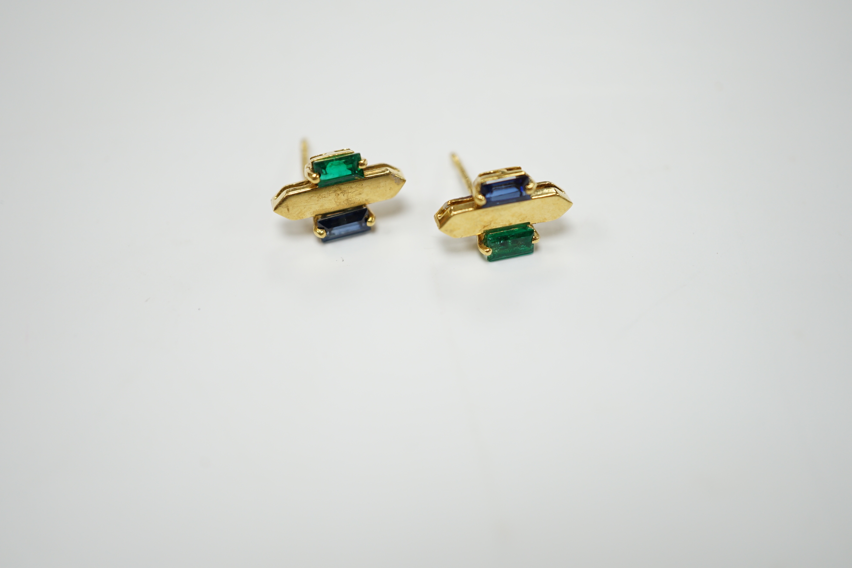 A modern pair of 18t gold, two emerald and sapphire set ear studs, 12mm by 7mm, gross weight 3.3 grams.